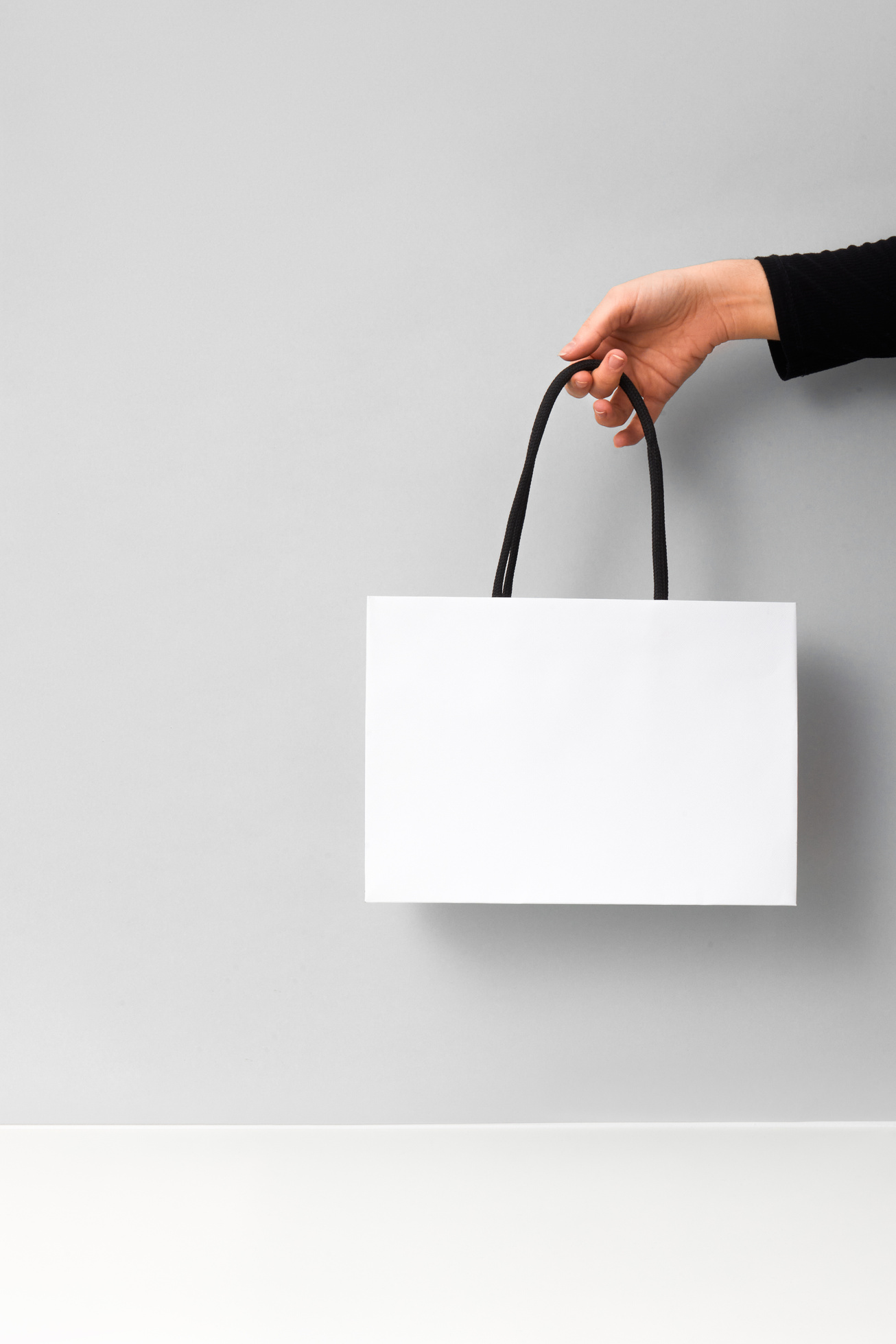 Person's Hand Holding a White Shopping Bag